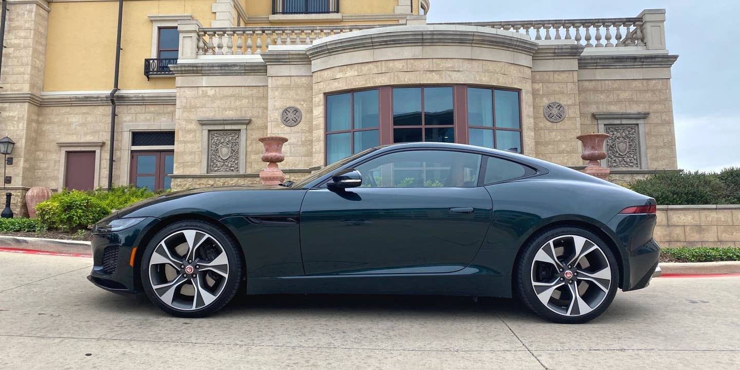 green Jaguar in front of tan building